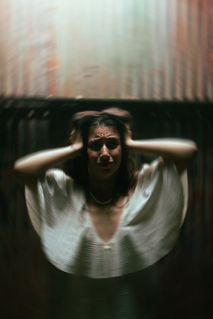 Blurred portrait of a woman expressing emotion, dramatic lighting indoors.